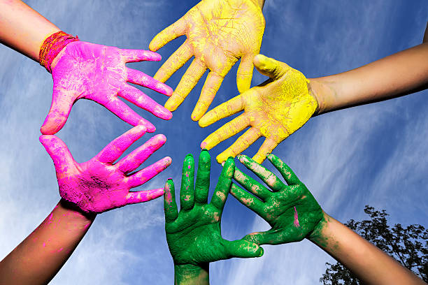 Young people hands covered in Holi Colors under blue sky