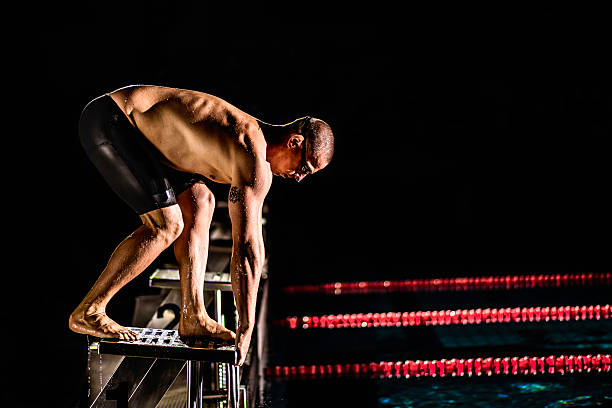 istock Swimmer Preparing To Jump Off The Starting Block 517536255