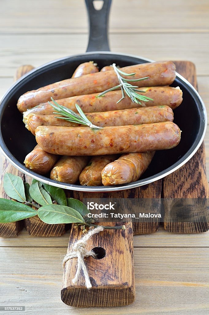 Thin sausages in a pan Thin fried sausages in a pan on a wooden background  Breakfast Stock Photo