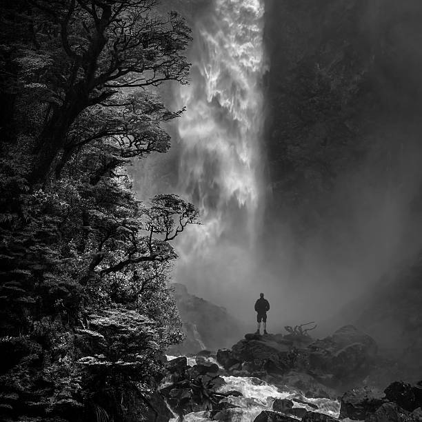 Devil's Punchbowl Man stands in awe in front of Devil's Punchbowl waterfall, Arthur's Pass N.P., New Zealand. psychedelic photos stock pictures, royalty-free photos & images