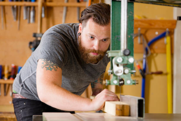 Craftsman using band saw for splitting wood plank in workshop