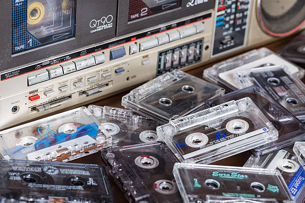 Old cassette tape recorder Sharp with cassettes. Zhytomyr, Ukraine, 24 March 2016. Cassette tape recorder Sharp model QT-90ZG with cassettes. The tape recorder was made in Japan for export. Cassettes are scattered on the table near the tape recorder. sharp corporation stock pictures, royalty-free photos & images