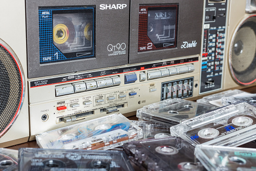 Zhytomyr, Ukraine, 24 March 2016. Cassette tape recorder Sharp model QT-90ZG with cassettes. The tape recorder was made in Japan for export. Cassettes are scattered on the table near the tape recorder.