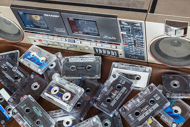 Old cassette tape recorder Sharp with cassettes. Zhytomyr, Ukraine, 24 March 2016. Cassette tape recorder Sharp model QT-90ZG with cassettes. The tape recorder was made in Japan for export. Cassettes are scattered on the table near the tape recorder. sharp corporation stock pictures, royalty-free photos & images