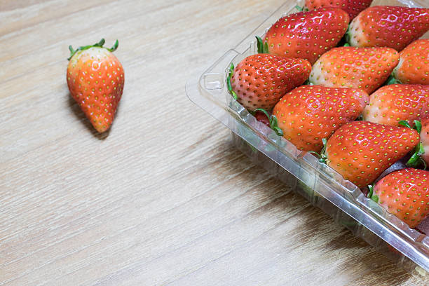 istock Strawberries in plastic pack on a wood background 517542186