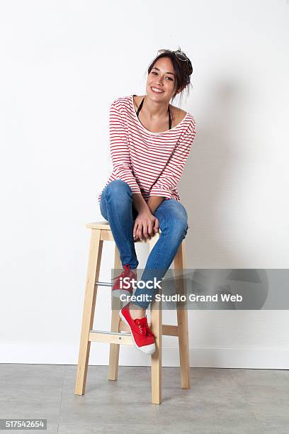 Thrilled Beautiful Ethnic Girl Sitting On Stool Enjoying Free Time Stock Photo - Download Image Now