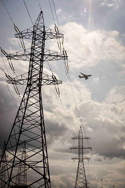 istock Electric tower and plane in the sky 517546098
