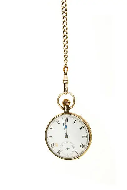 Antique pocket watch hanging from a chain against white