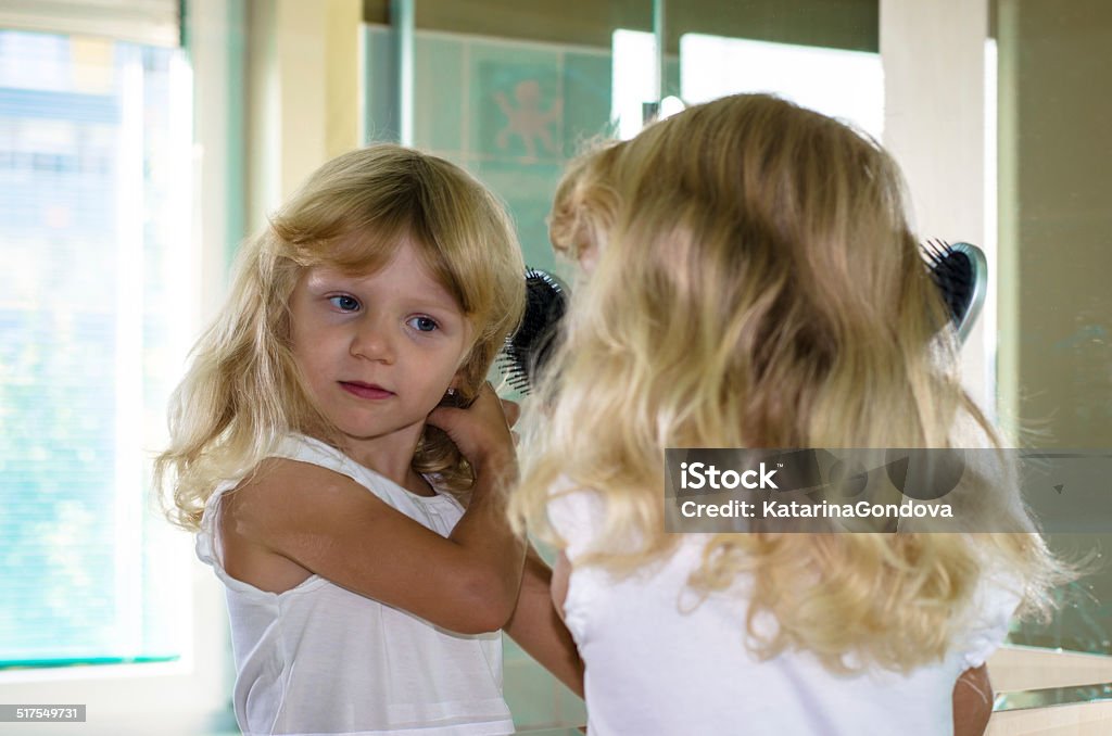 blond girl brushing hair beautiful blond girl with long hair brushing her hair in the mirror Bathroom Stock Photo