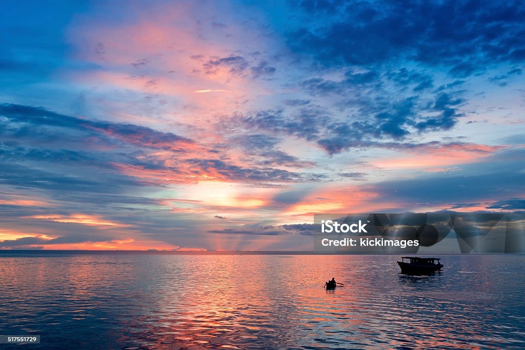 Sunset Boat Rowing Silhouette Of People rowing boat in sea with dramatic sunset sky. Beauty In Nature Stock Photo