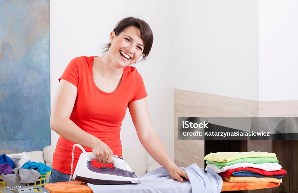 Smiling woman ironing clothes Smiling young woman ironing clothes at home, horizontal Adult Stock Photo