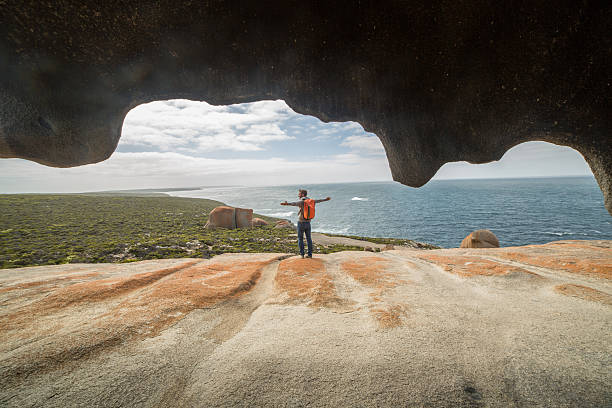 Cheerful young man arms outstretched at The Remarkable rocks, located in Flinder's  chase National park on Kangaroo Island, SA, Australia.