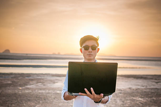 istock Business man working with laptop and smartphone beach background 517570810