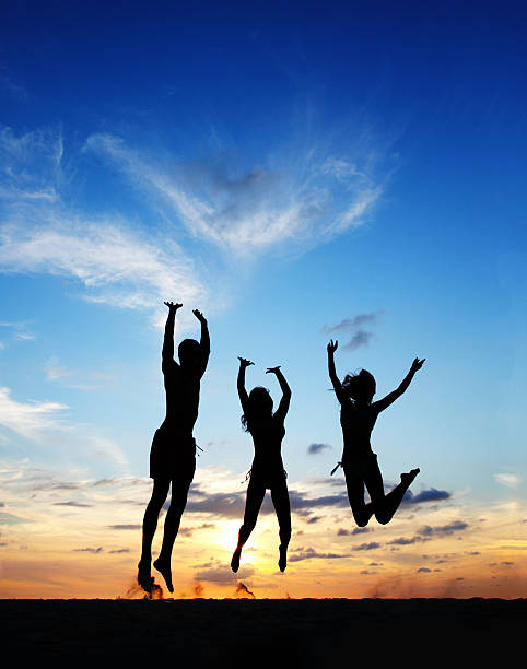 istock People jumping at sunset beach 517573040