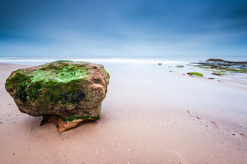 Red rock formation at Exmouth beach in Devon, UK. Long exposure blured sea water.