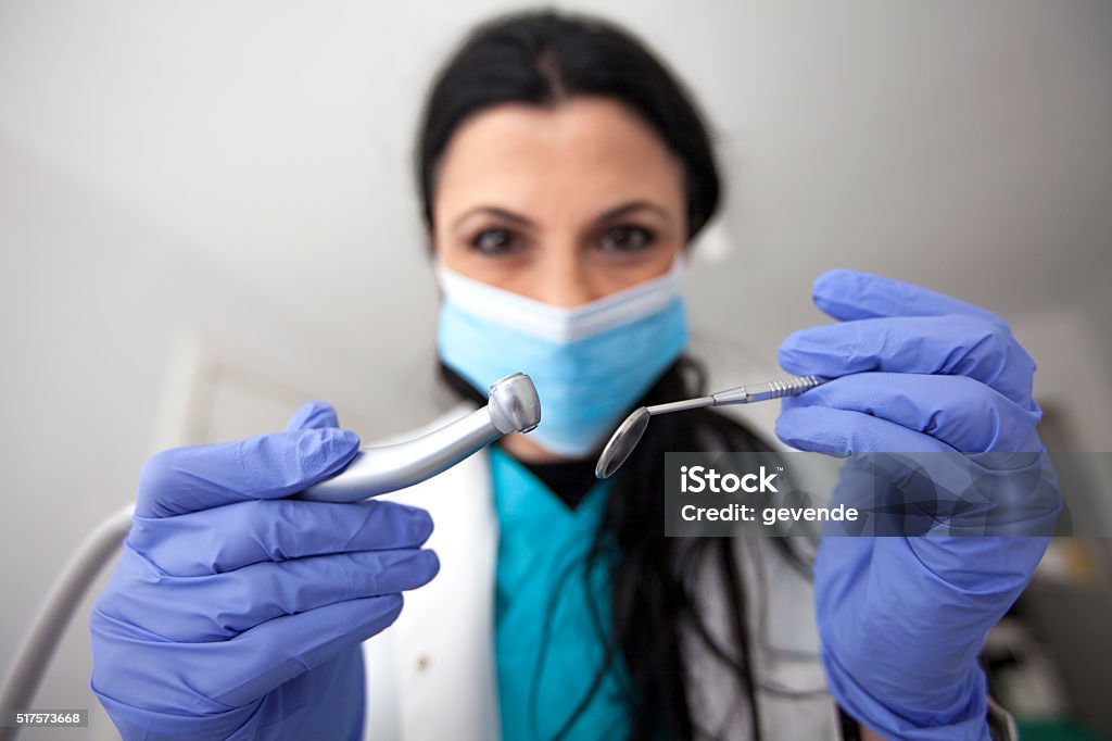 Dentist at work Female dentist looking at the patient and holding dental equipment. 20-29 Years Stock Photo