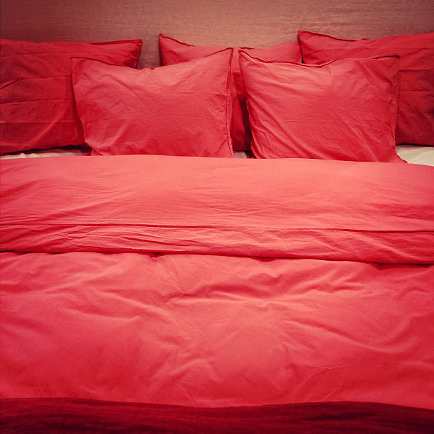 Red romantic bed linen Bed with red romantic bed linen and lots of pillows. red cushion covers stock pictures, royalty-free photos & images