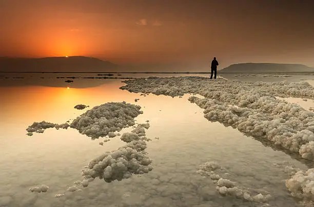 A sunrise at the Dead-Sea with a silhouette of a photographer in the background