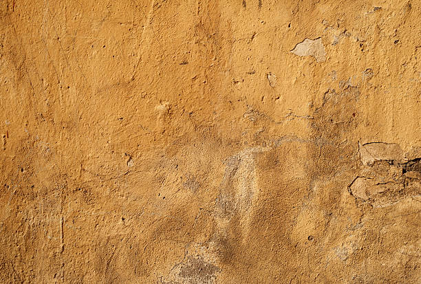 istock Texture of old wall covered with yellow stucco 517575737