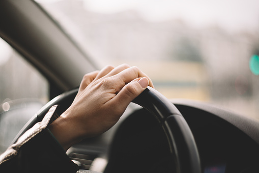 Close-up of a woman's hand driving a car