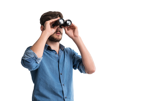 Tourist with hiking equipment looking through binoculars in mountains