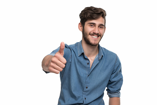 Young man giving thumbs up over isolated white background. Image taken with Sony A7RII camera system and developed from camera RAW