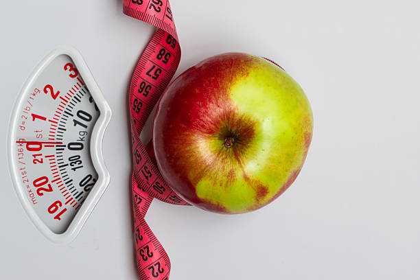istock Apple with measuring tape on weight scale. Dieting 517580466