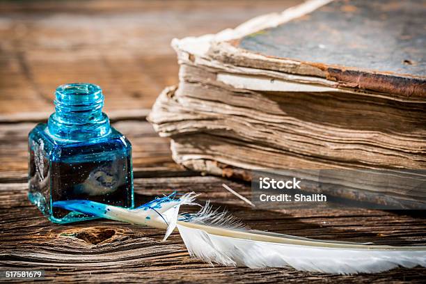 White Feather On Blue Inkwell And Old Book Stock Photo - Download Image Now - Ancient, Antique, Book
