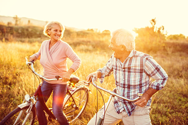 senior sorridente casal equitação bicicletas - action mature adult bicycle senior couple imagens e fotografias de stock
