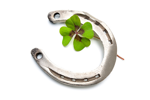 Horseshoes and four leaf clover on white background