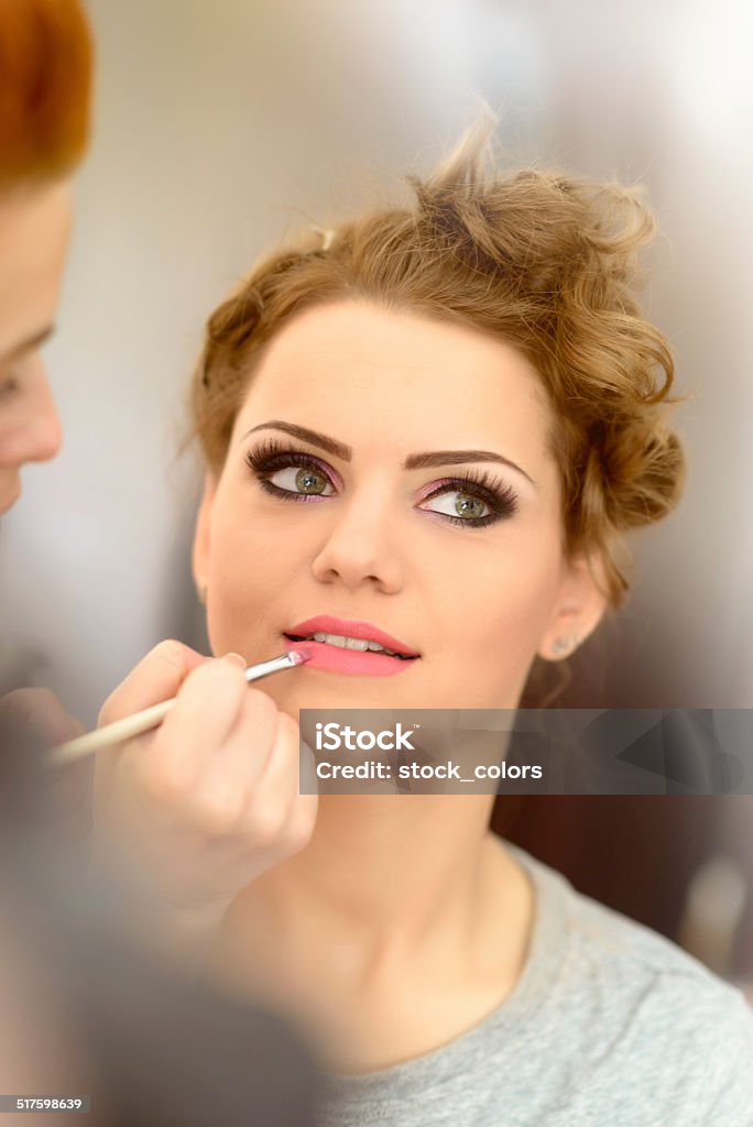 applying lipstick woman portrait applying lipstick at makeup salon. Adult Stock Photo