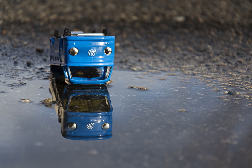 Prague, Czech republic - March 23, 2016: Vintage tinwork toy car with Volkswagen logo in puddle in front of dealership on March 23, 2016 in Prague, Czech republic.