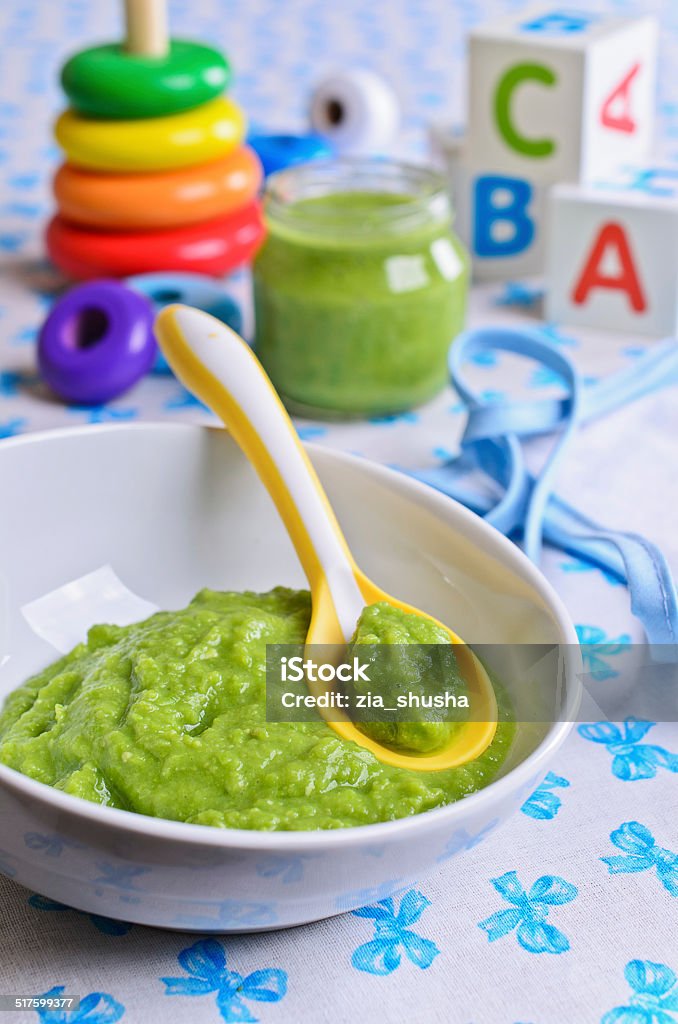 Food for children Puree of green in the small bowl is on the background of childrens toys Baby - Human Age Stock Photo