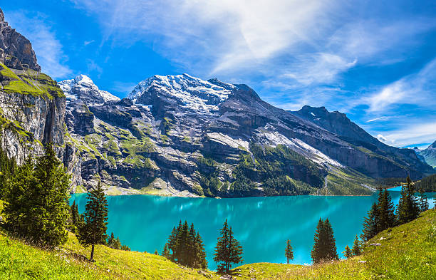 Panorama view of Oeschinensee (Oeschinen lake) on bernese oberla The panorama in summer view over the Oeschinensee (Oeschinen lake) and the alps on the other side near Kandersteg on Bernese Oberland in Switzerland. lake oeschinensee stock pictures, royalty-free photos & images