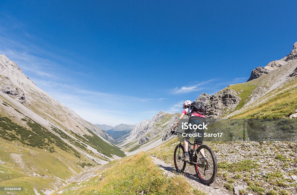 Narrow Single Trail Biking, Switzerland A female mountainbiker on a narrow single Trail at the Welschtobel Valley leading to the City of Arosa, Switzerland. Arosa Stock Photo