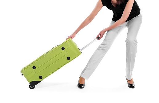 Woman drags a heavy suitcase on a white background.