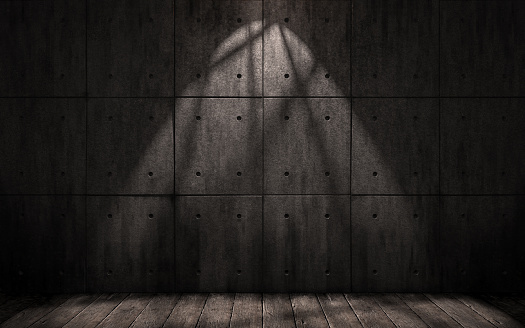a dark underground room with walls of concrete slabs and wooden floor