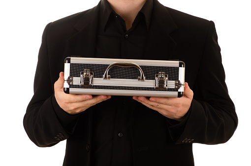 man keeps a metal case in a black jacket and a black shirt horizontally