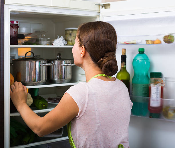 istock brunette in apron looking at products in refrigerator 517613954