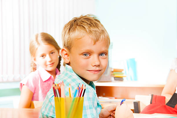istock Smiling boy sitting at desk with girl classmate 517619069
