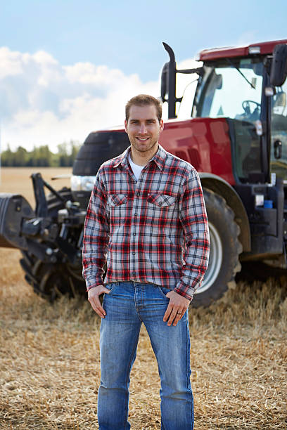 istock Farmer standing in front of tractor in a field 517620229