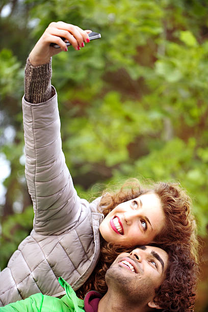 pareja mirando y sonriendo para un divertido autofoto - double click fotos fotografías e imágenes de stock