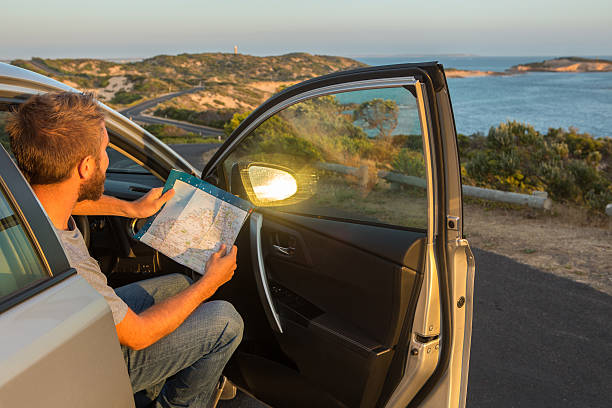 istock Young man in a car check directions on road map 517629686