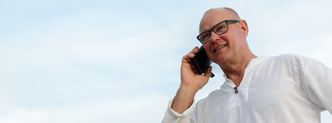 Handsome senior man using phone outdoors