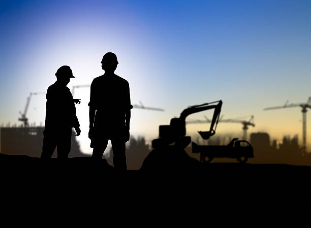 istock silhouette engineer looking Loaders and trucks in a building sit 517631186