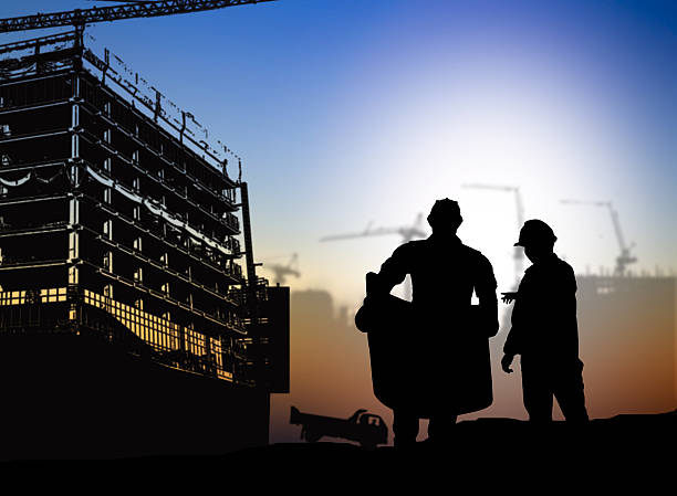 istock silhouette engineer looking blueprint in a building site over Bl 517636742