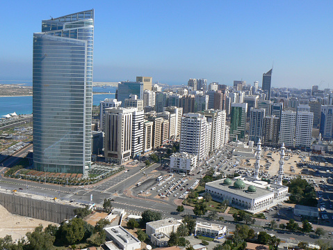 Modern high rise buildings and old mosques together in the Middle Eastern city of Abu Dhabi, United Arab Emirates