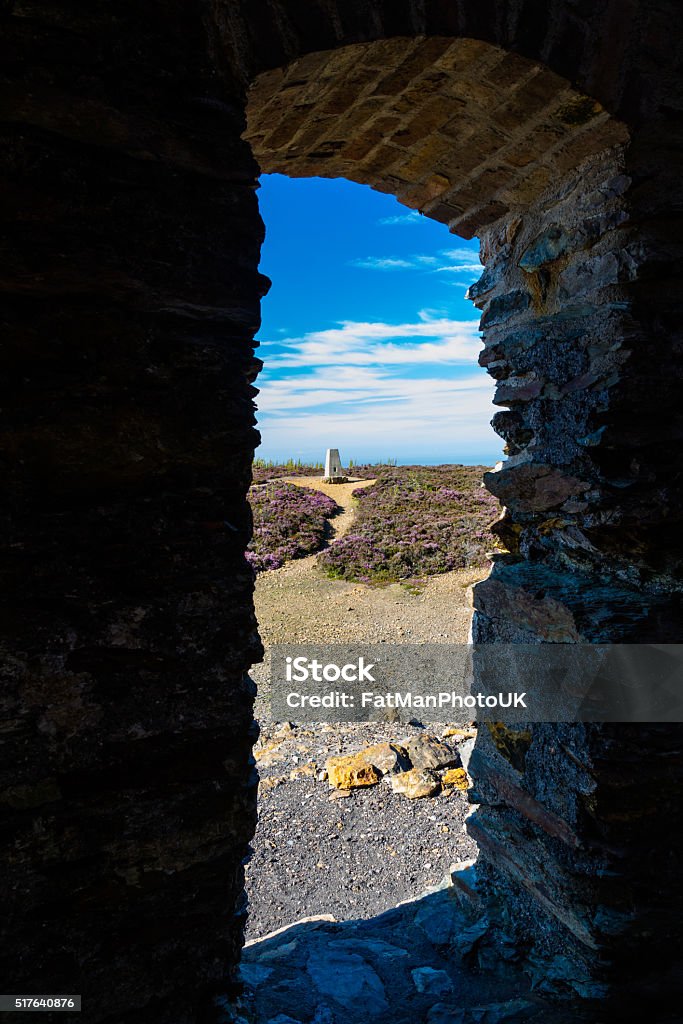 Trig point seen through arch, Parys Mountain. Triangulation point, Parys Mountain, Amlwch, Anglesey, Wales, United Kingdom Abandoned Stock Photo