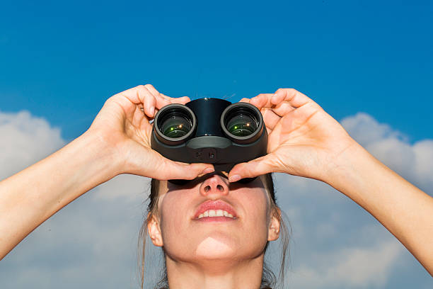istock Cute young woman looking through binoculars 517642881