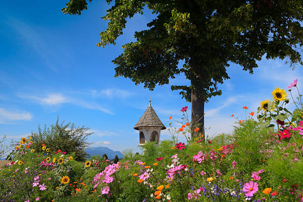 colourful flowers with the Egger Marterl, a religious wayside shrine, in the background; Egg am See, Austria
